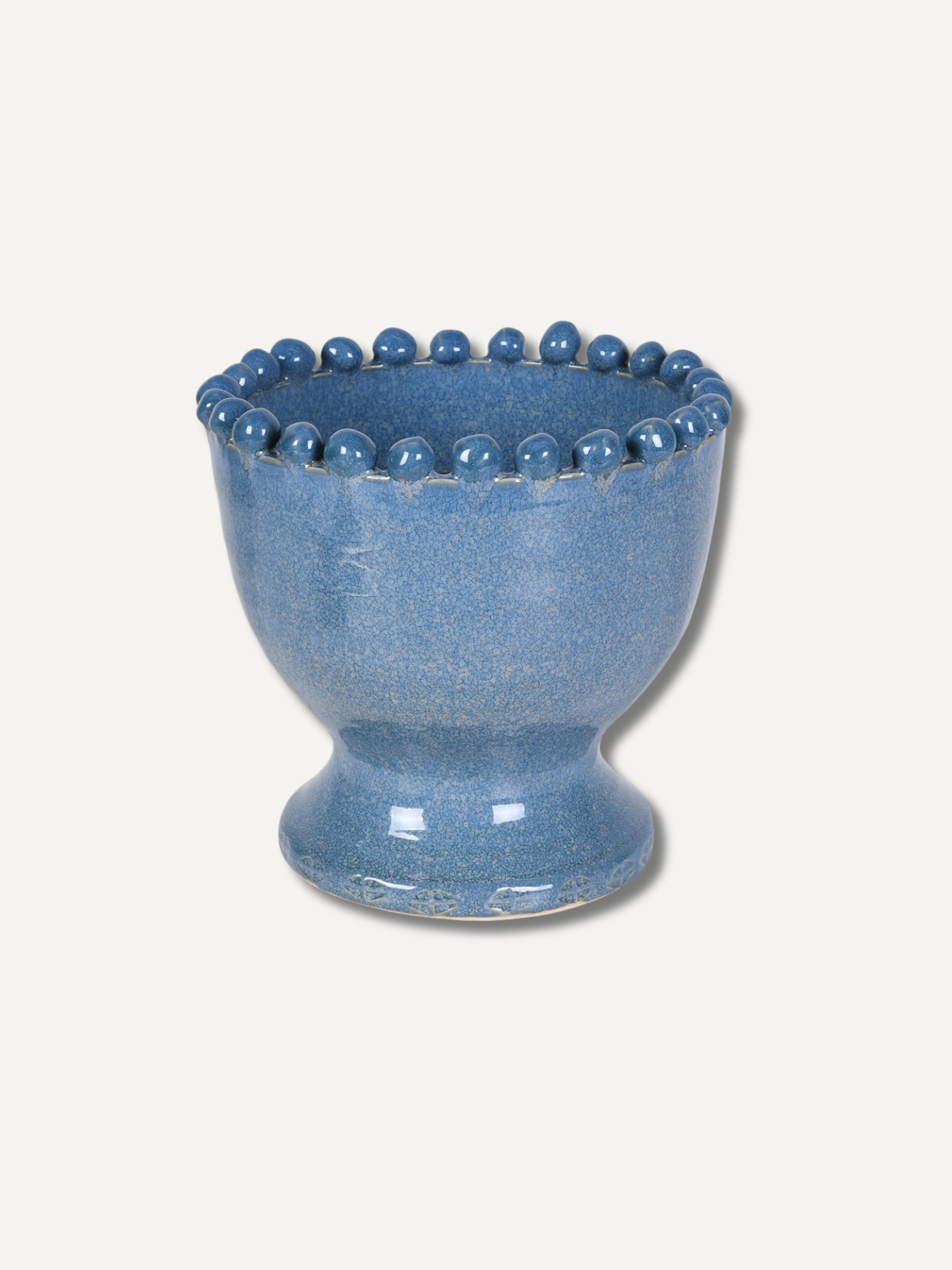 A small blue ceramic vase with a flared rim decorated with a row of raised round beads, shown on a plain light beige background.