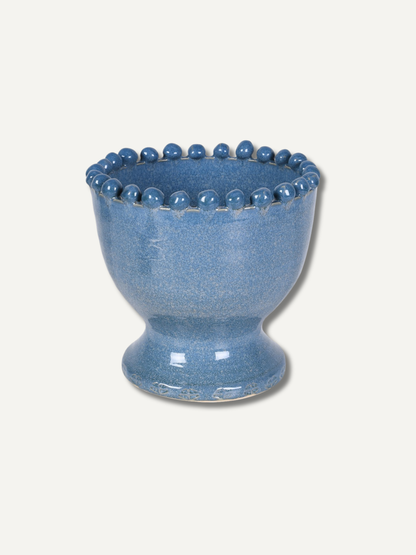 A small blue ceramic vase with a flared rim decorated with a row of raised round beads, shown on a plain light beige background.