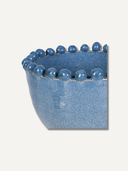 A blue speckled ceramic planter with a raised rim decorated with a row of glossy blue beads, shown against a light beige background.