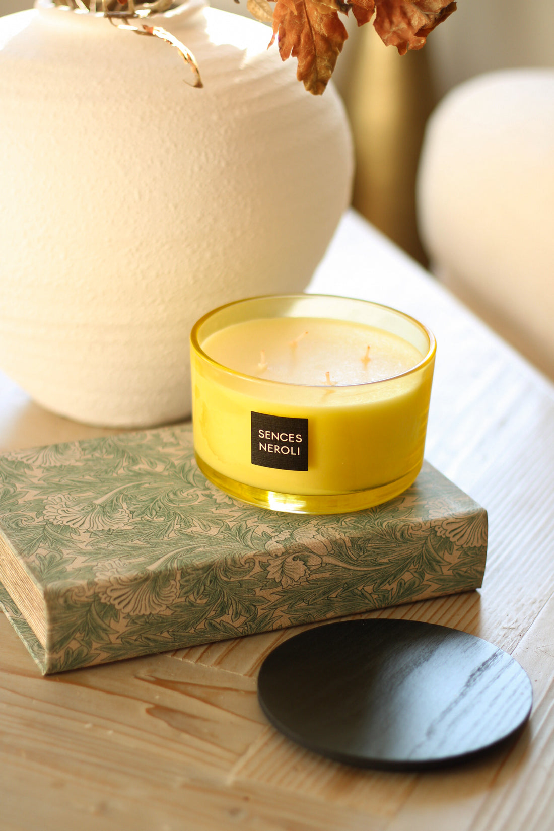 Neroli yellow candle with a label on a decorative box on a wooden surface