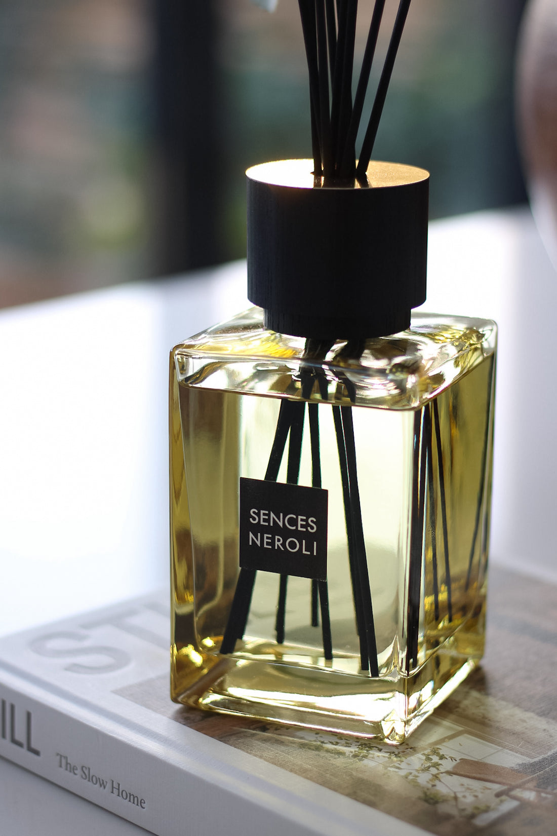 Sences Neroli diffuser bottle with black reeds on a light surface