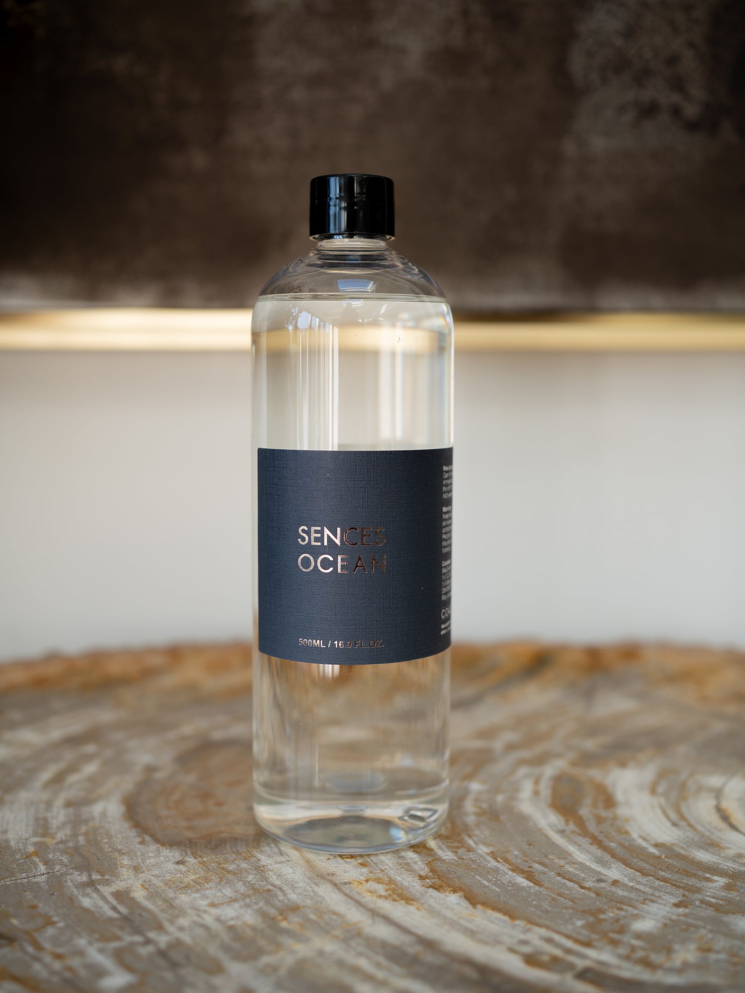 A clear refill bottle of diffuser oil with a black cap and a dark navy label reading &
