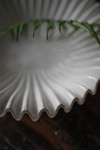 White ceramic plate with wavy edge on a dark background