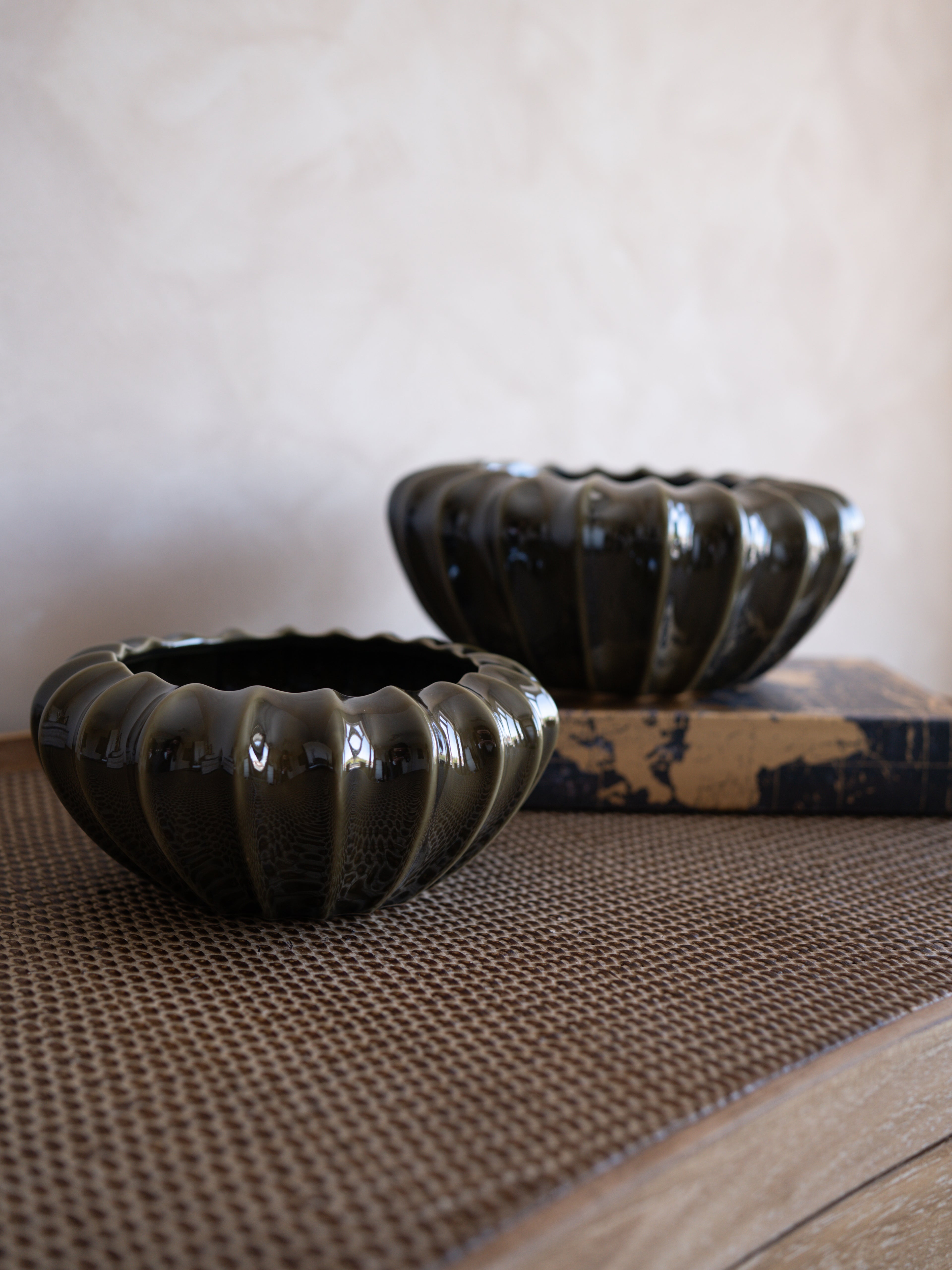 Two olive green ceramic bowls on a textured surface with a neutral background