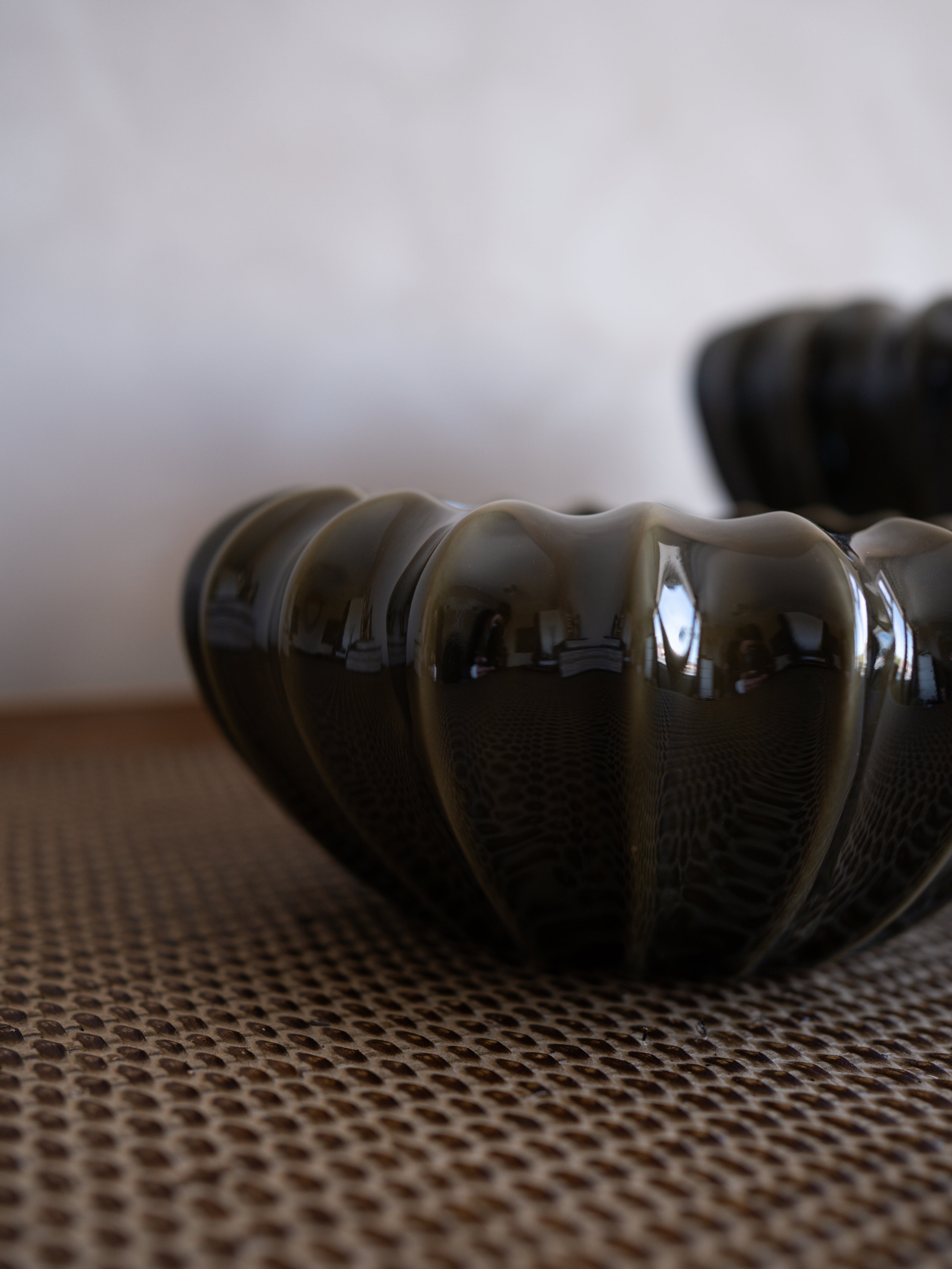 Olive green textured vase on a woven surface with a blurred background