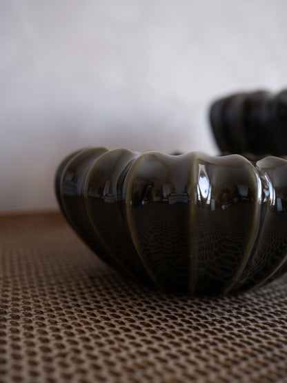 Olive green textured vase on a woven surface with a blurred background