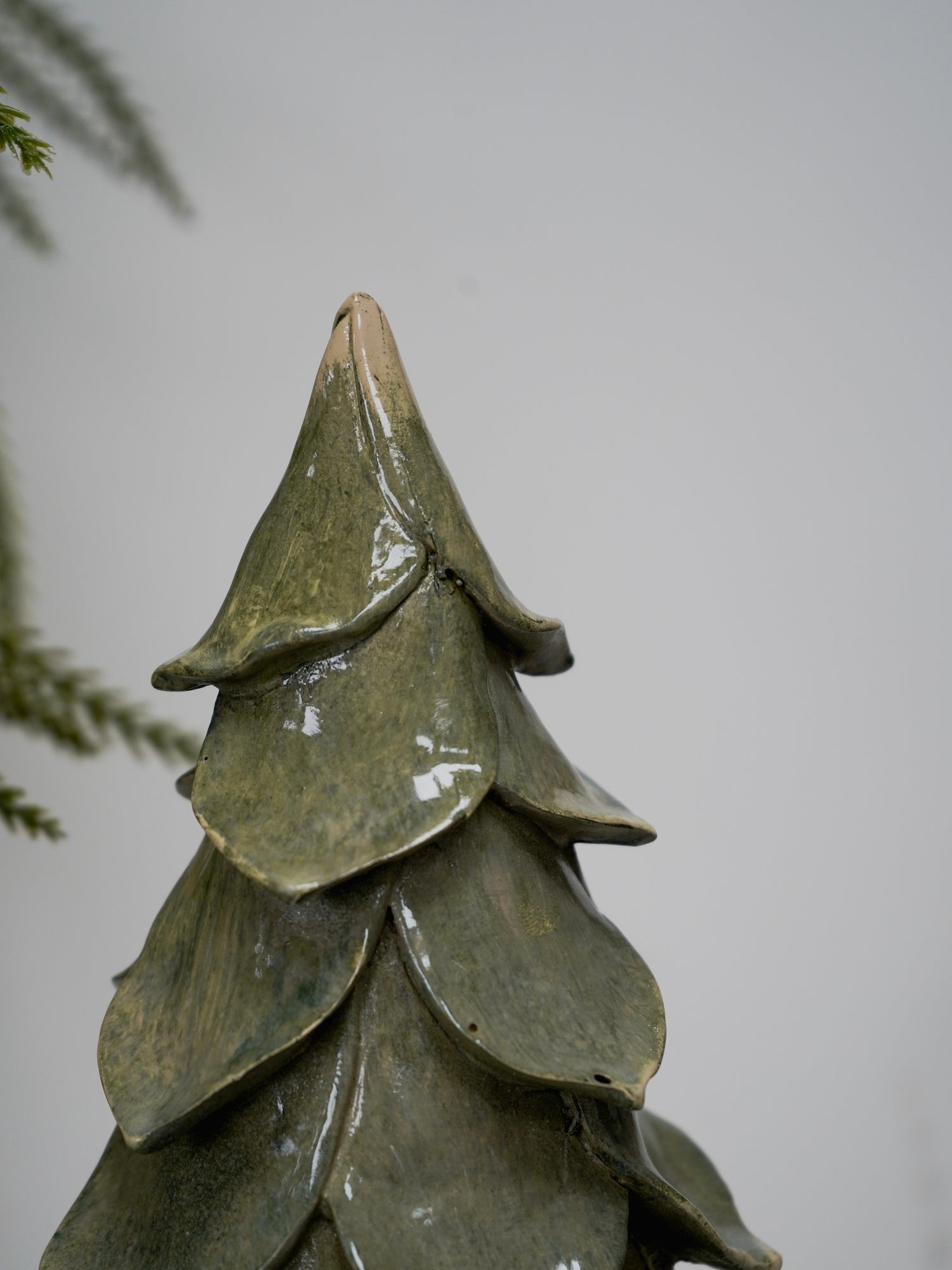 Green ceramic tree-shaped ornament on a plain background