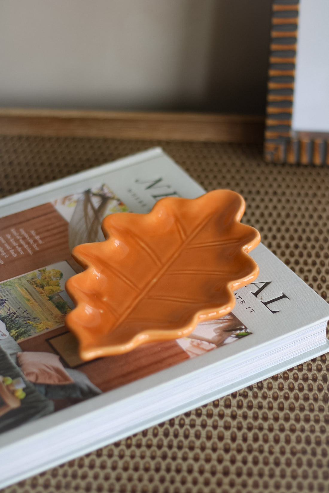 Orange leaf-shaped dish on a magazine with a blurred background