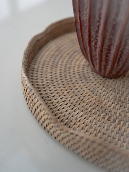 Woven rattan coaster with a striped vase on a light background