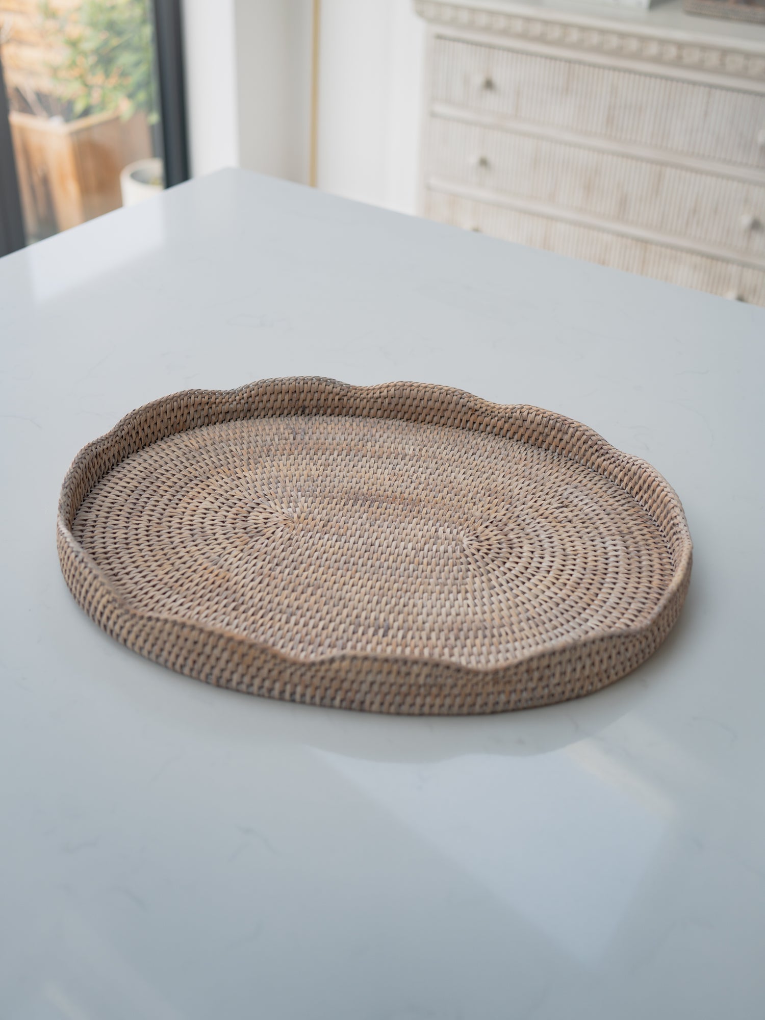 Round woven tray on a light gray surface with a blurred background