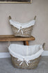 Two wicker baskets with white liners on a wooden shelf against a beige wall.