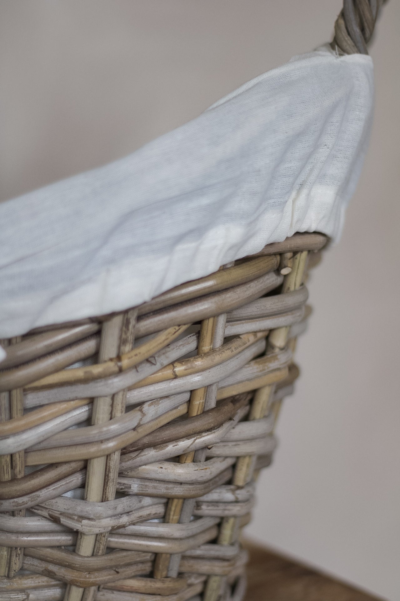 Woven basket with a white cloth inside against a neutral background