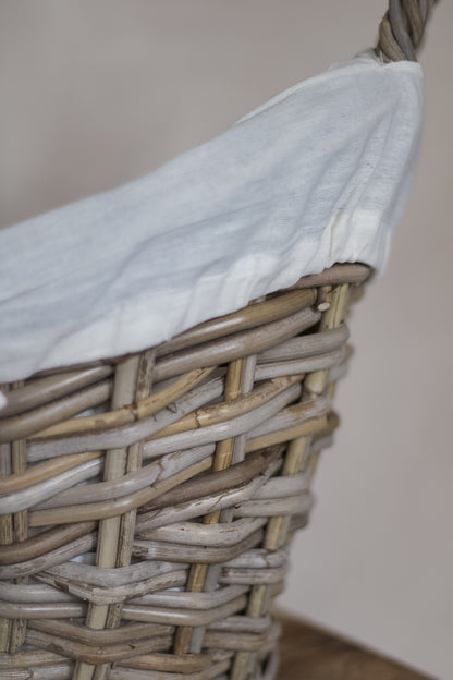 Woven basket with a white cloth inside against a neutral background