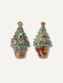 Two small decorative Christmas tree ornaments shaped like potted trees, shown on a plain light background. One tree has a red bow and holiday ornaments, and the other has a red bow with a dog figure on the tree.