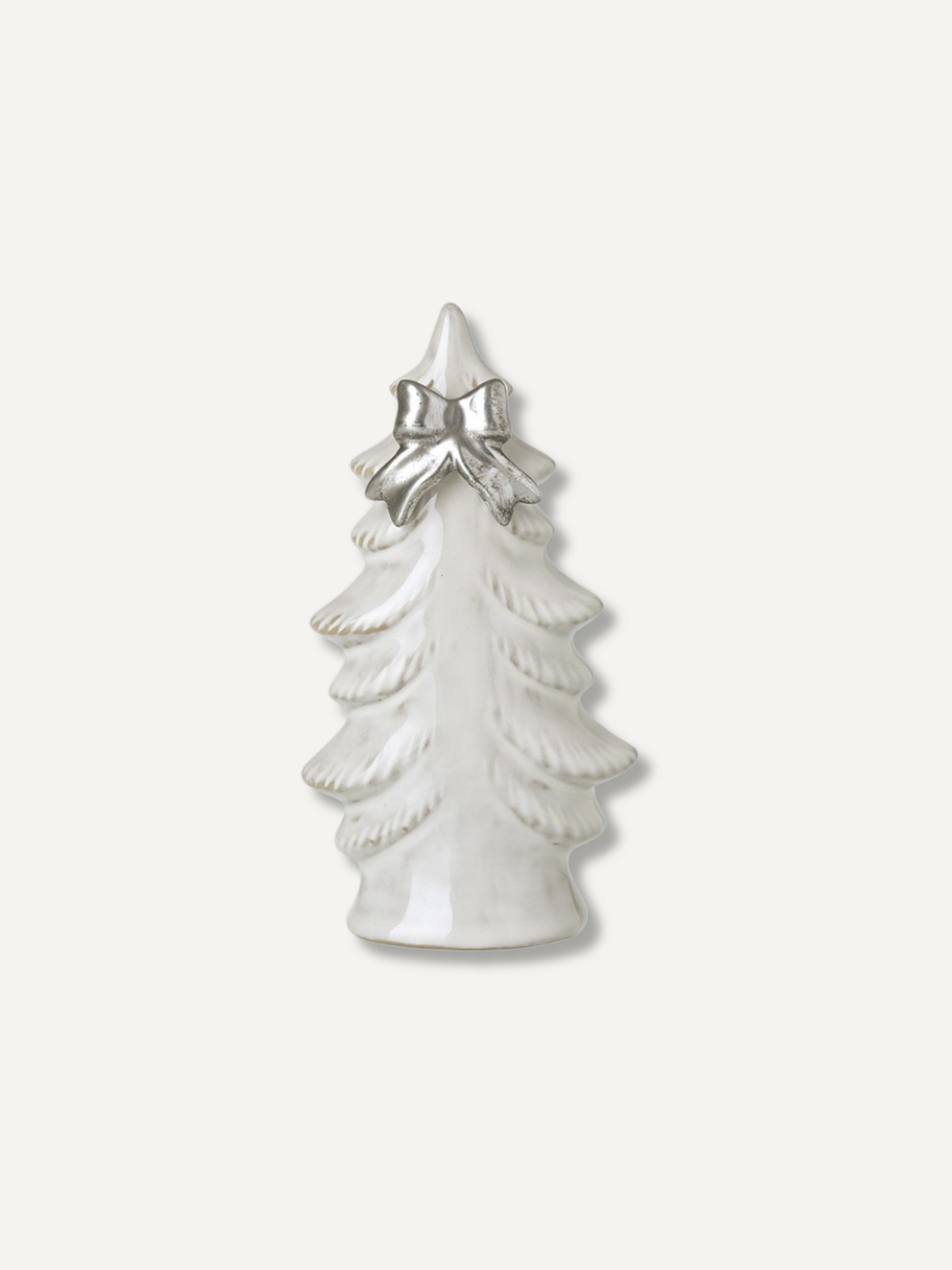 A small white ceramic Christmas tree figurine with a textured layered design and a shiny silver bow at the top, set against a plain off-white background.