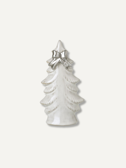 A small white ceramic Christmas tree figurine with a textured layered design and a shiny silver bow at the top, set against a plain off-white background.