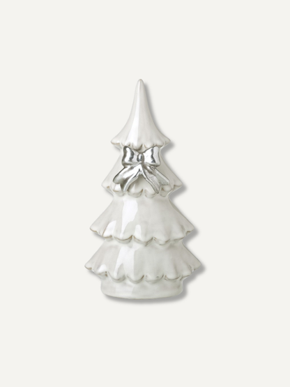 A small white ceramic Christmas tree figurine with a shiny silver bow accent, set against a plain off-white background.
