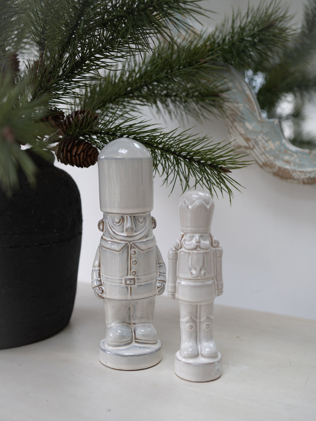 Pair of Stoneware Nutcrackers with faux fir pine branch in the background