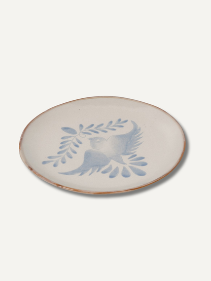 Ceramic plate with blue bird and leaf design on a white background