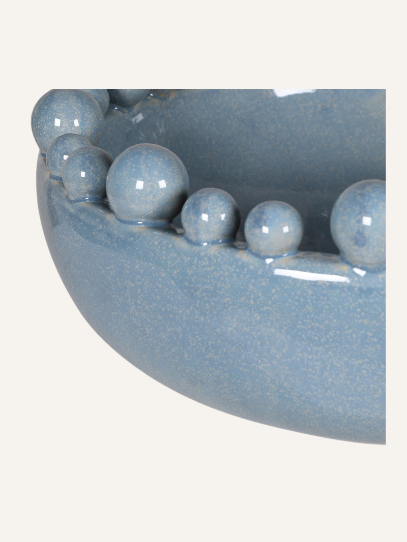 Pale blue ceramic bowl with bobble decorations on a white background