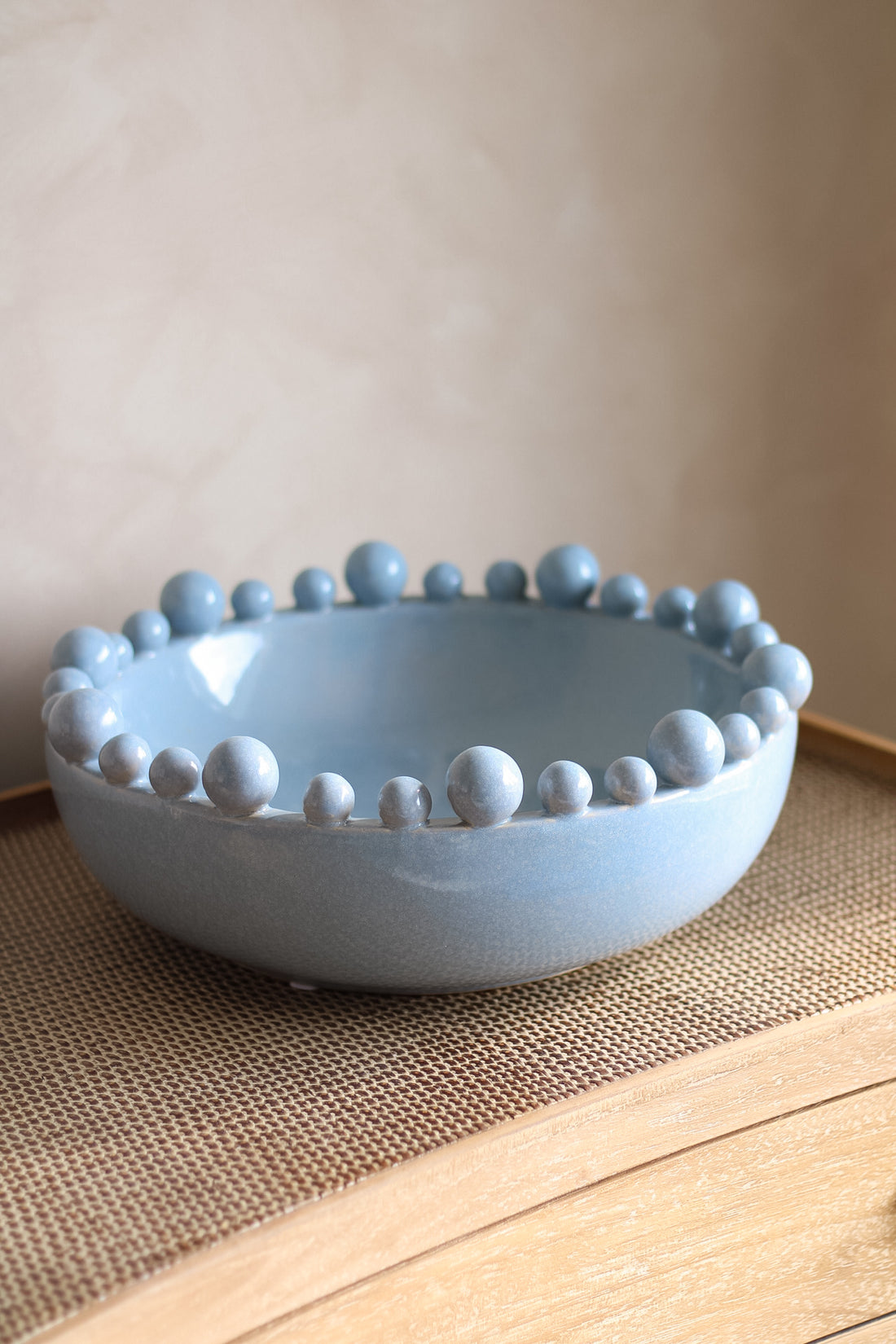 Light blue ceramic bowl with bobble edge on a wooden surface.