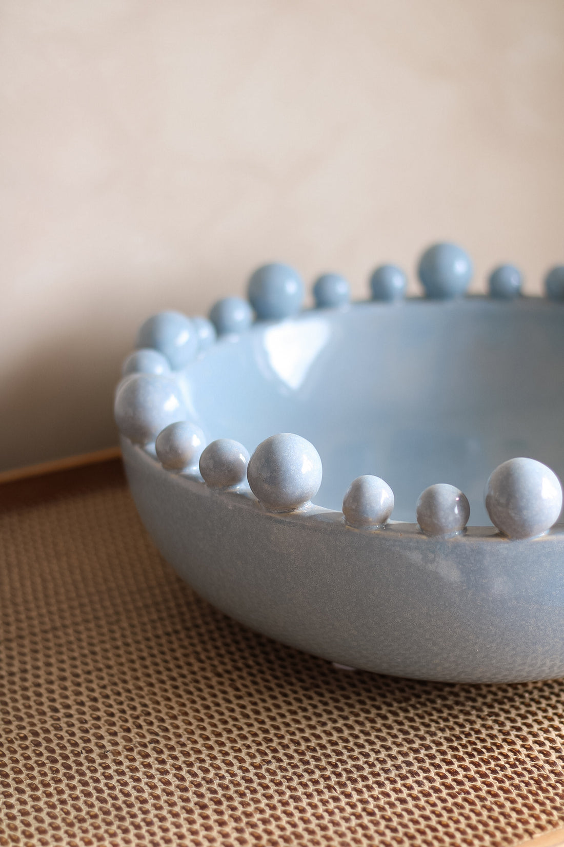 Ceramic bowl with bobble edged detail on a textured surface