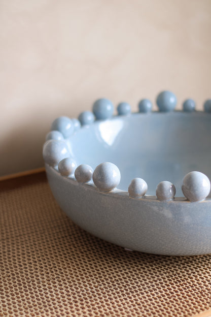 Ceramic bowl with bobble edged detail on a textured surface