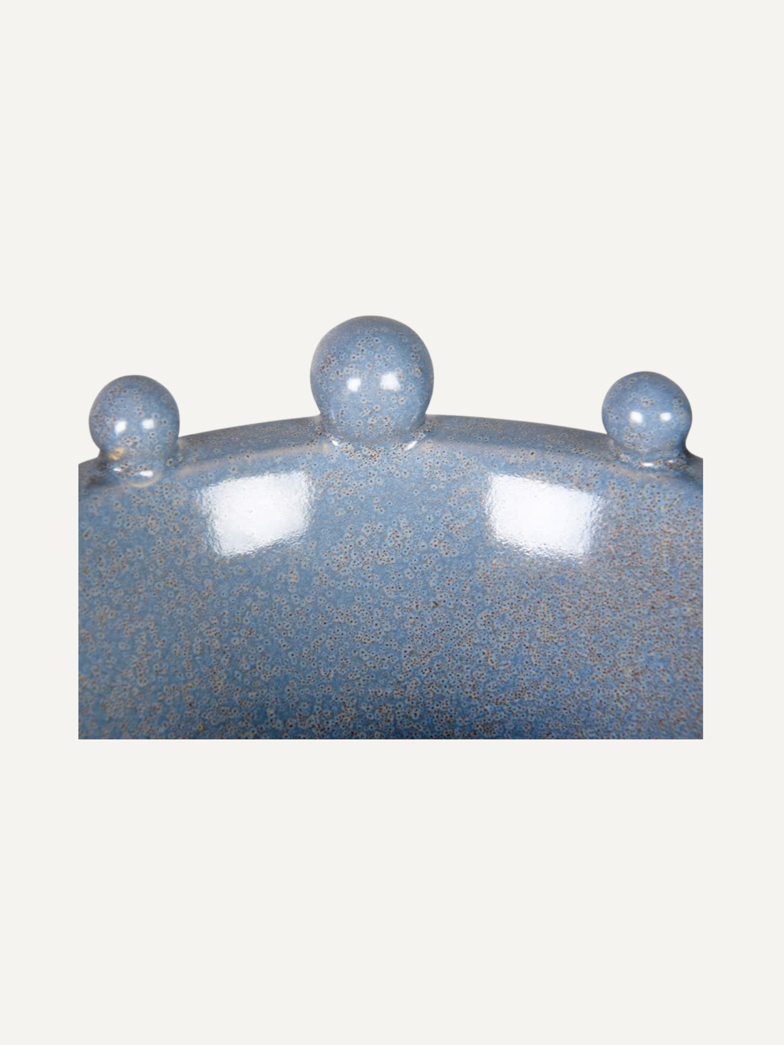 Blue speckled ceramic bowl with spherical bobbles on a white background