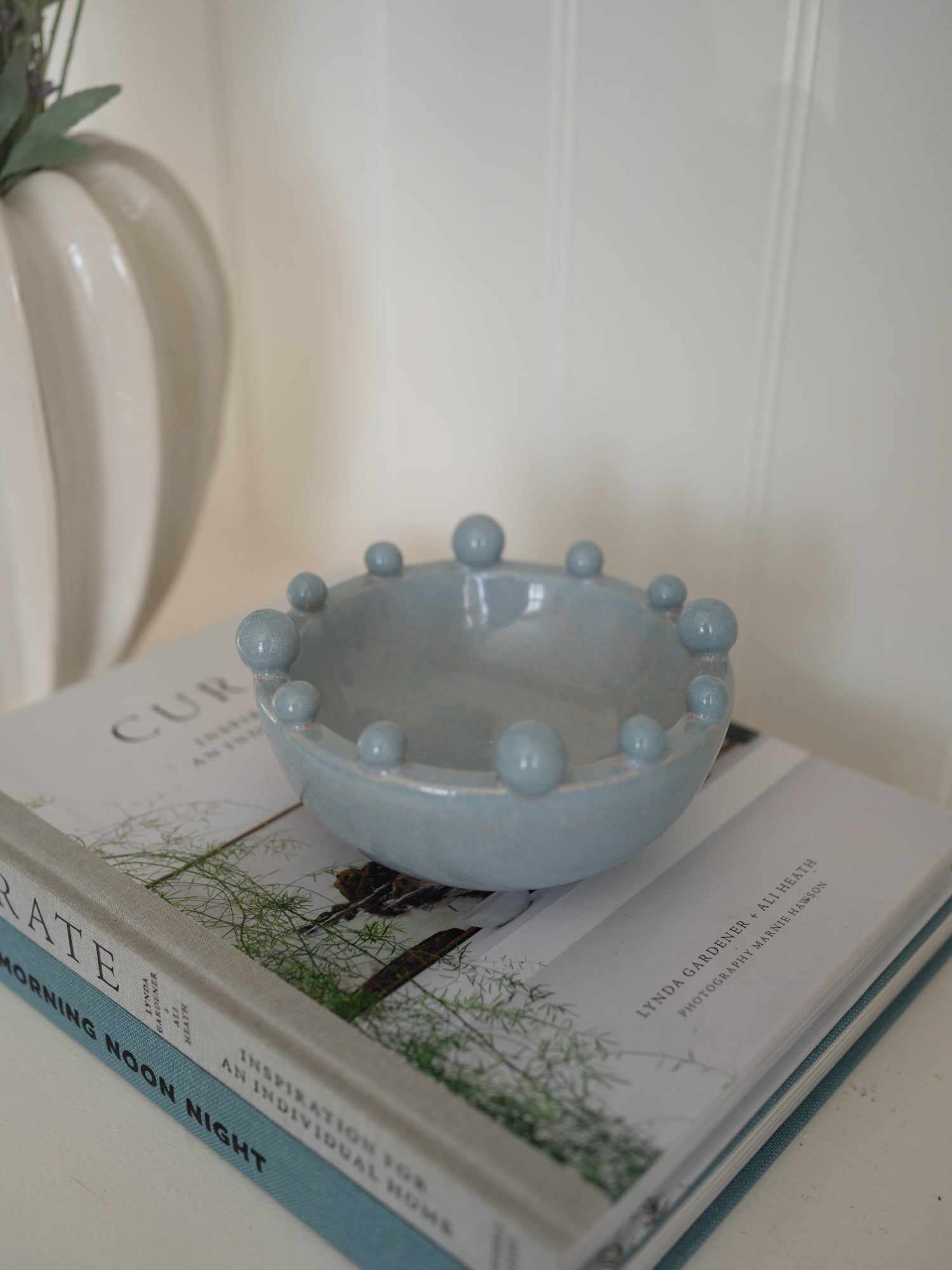 Light blue ceramic bowl with spherical bobbles on a stack of books