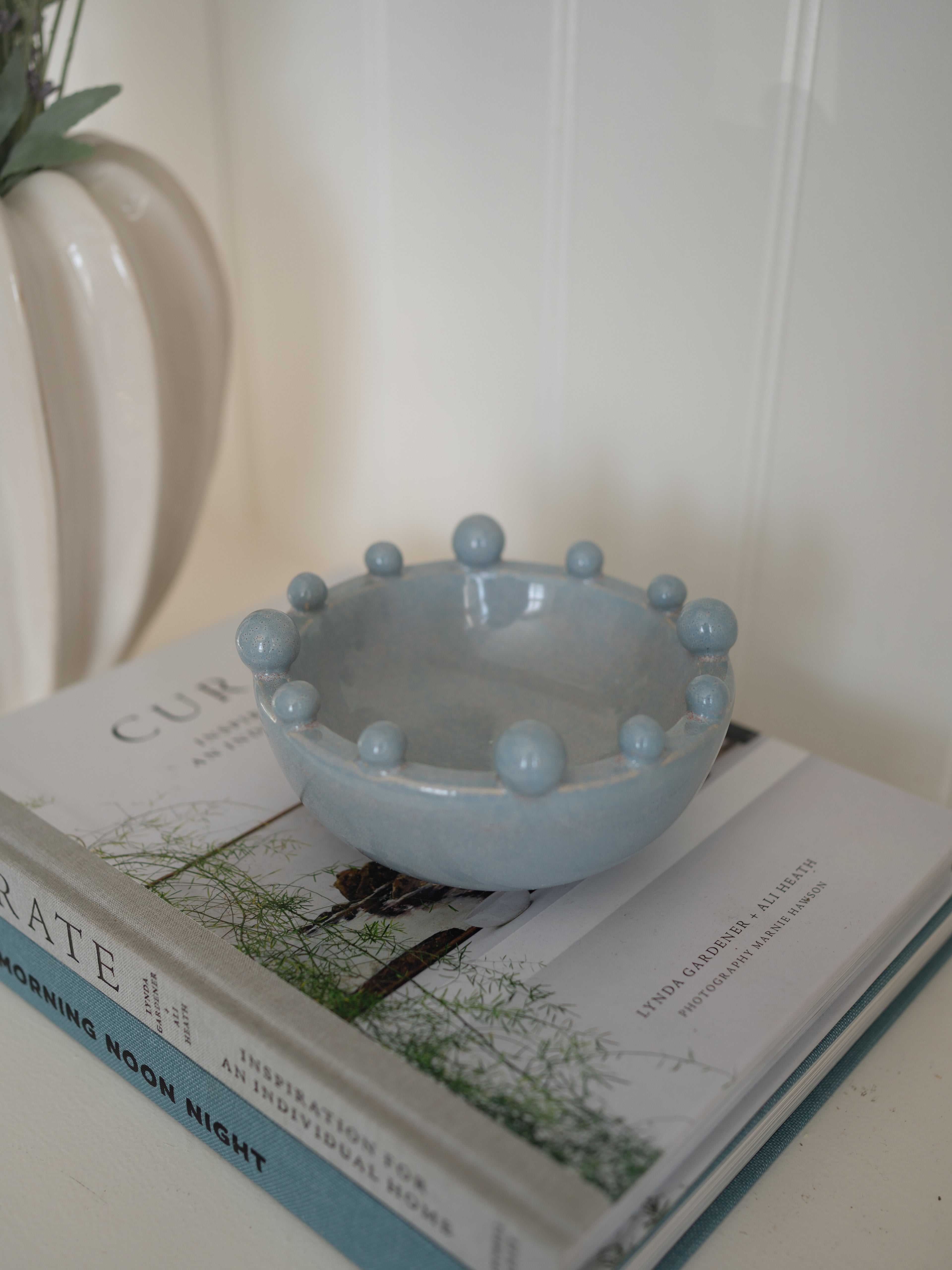 Light blue ceramic bowl with spherical bobbles on a stack of books