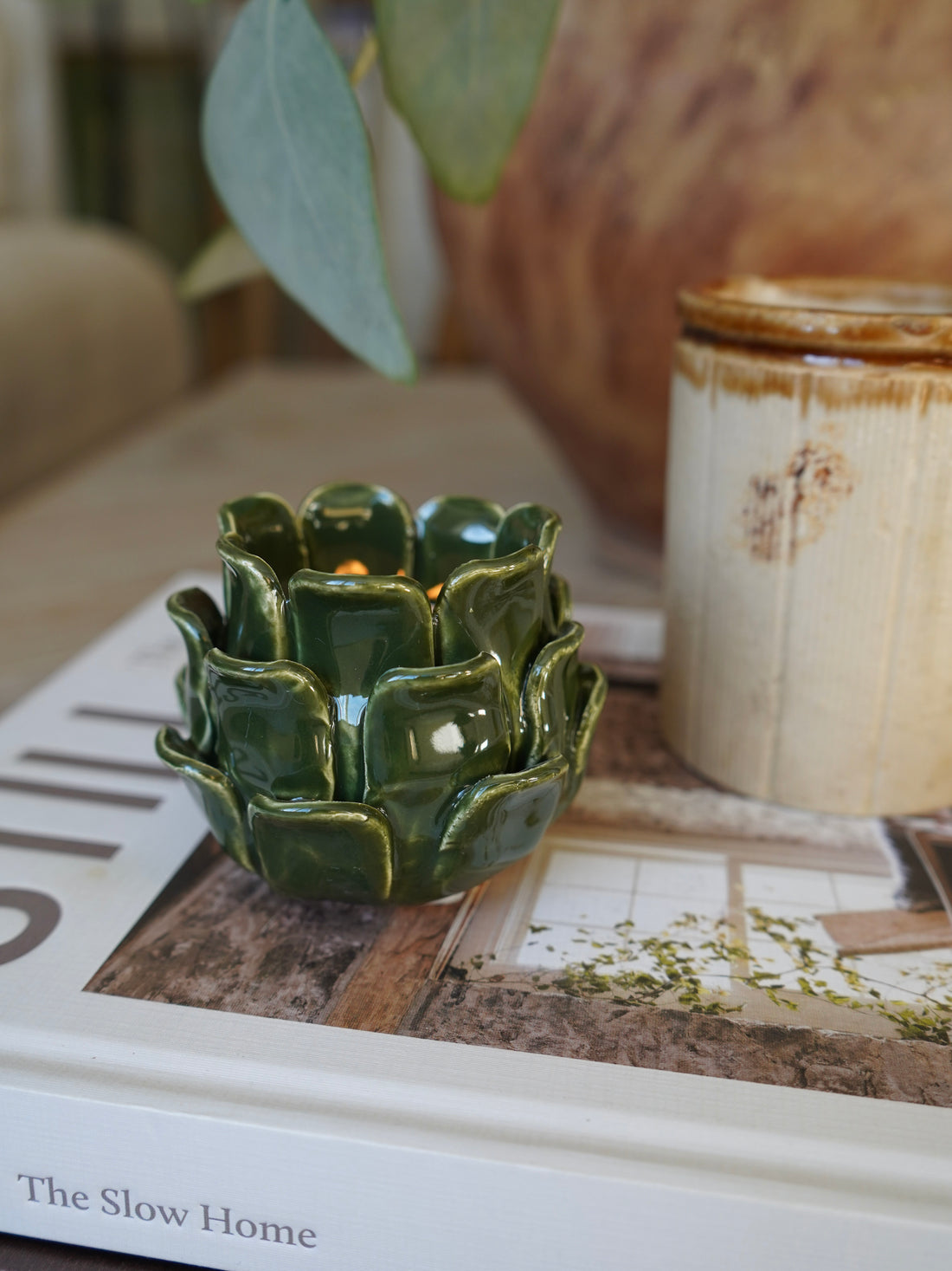 Green ceramic candle holder on a book with a blurred background