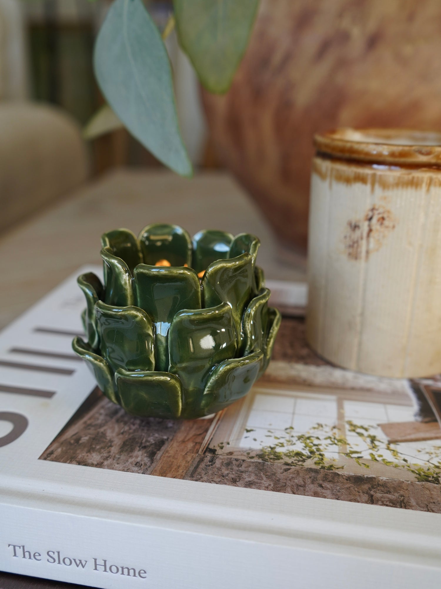 Green ceramic candle holder on a book with a blurred background