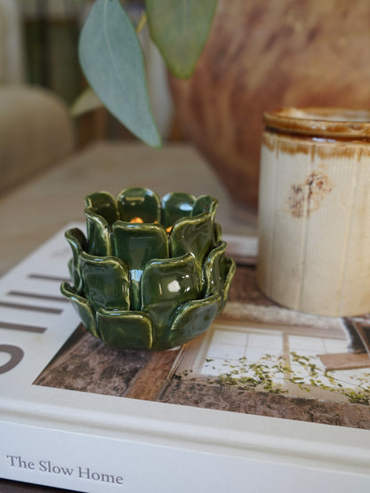 Green ceramic candle holder on a book with a blurred background
