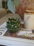 Green ceramic candle holder on a book with a blurred background