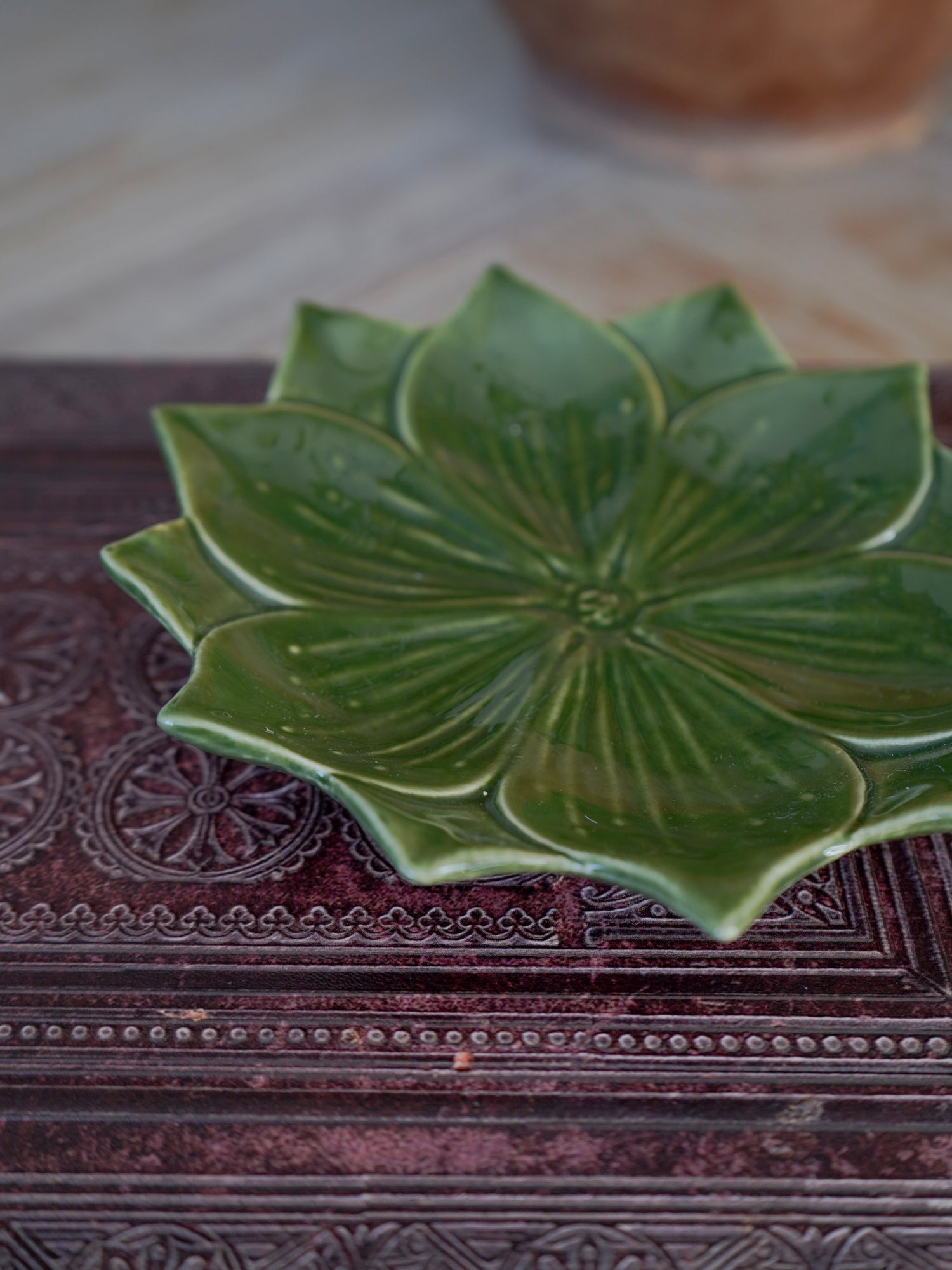 Green ceramic trinket dish with leaf-like design on a textured surface