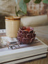 Decorative plum candle holder on a book with a blurred background