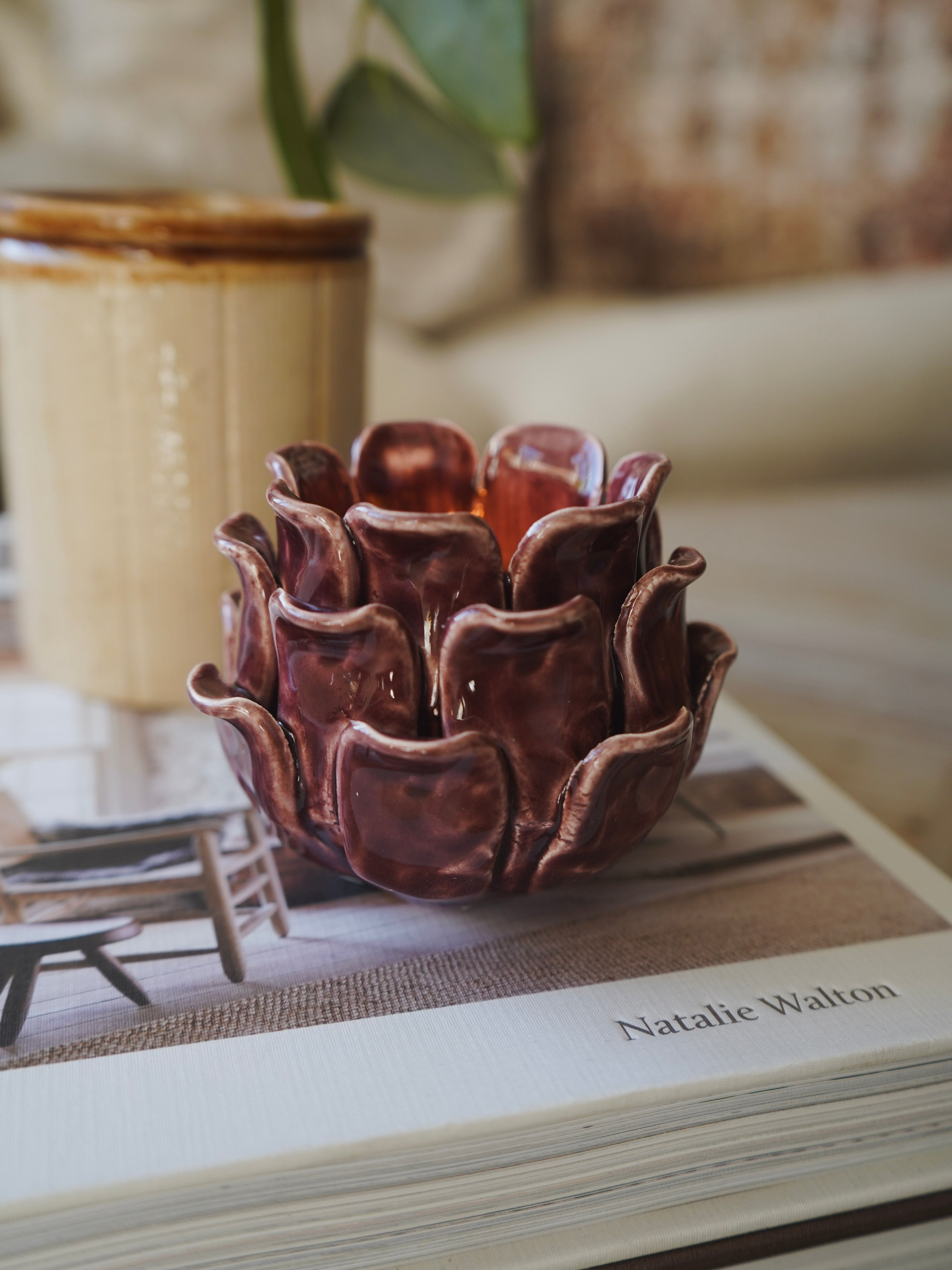 Brown ceramic flower-shaped container on a book with a blurred background
