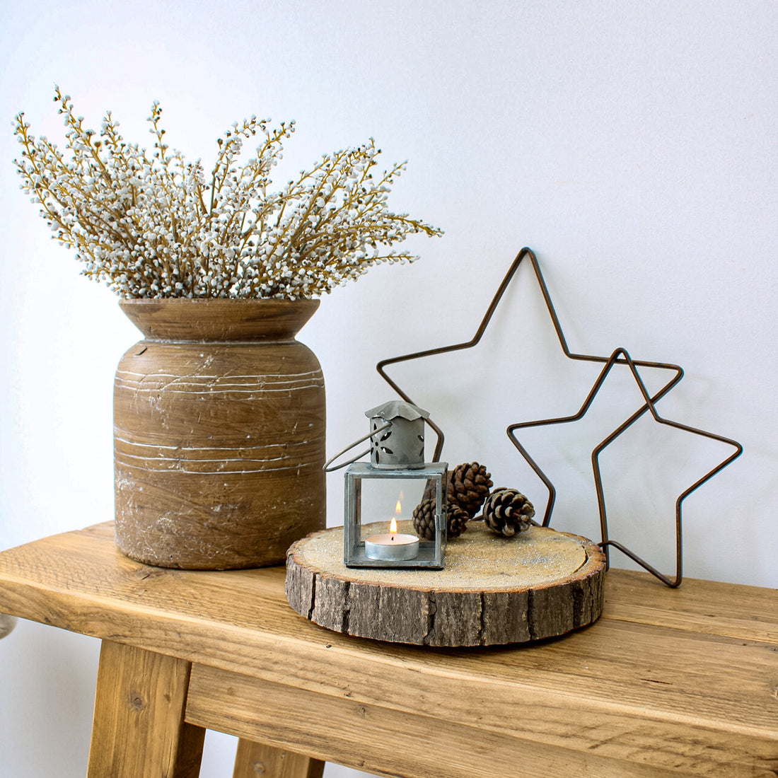 small silver lantern with pattern detail, brass stars and brown rustic vase with faux heather stems