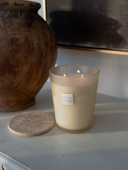 A lit frosted glass candle with a small white label reading &