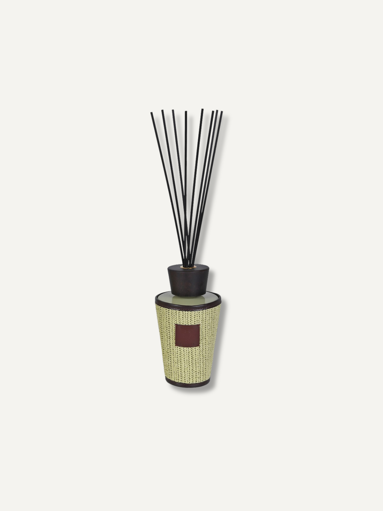A reed diffuser with a textured light beige and black cylindrical bottle, a dark cap, and several black reeds, shown against a solid off-white background.