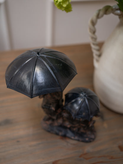 Decorative figurine of three rabbits under an umbrella on a wooden surface.