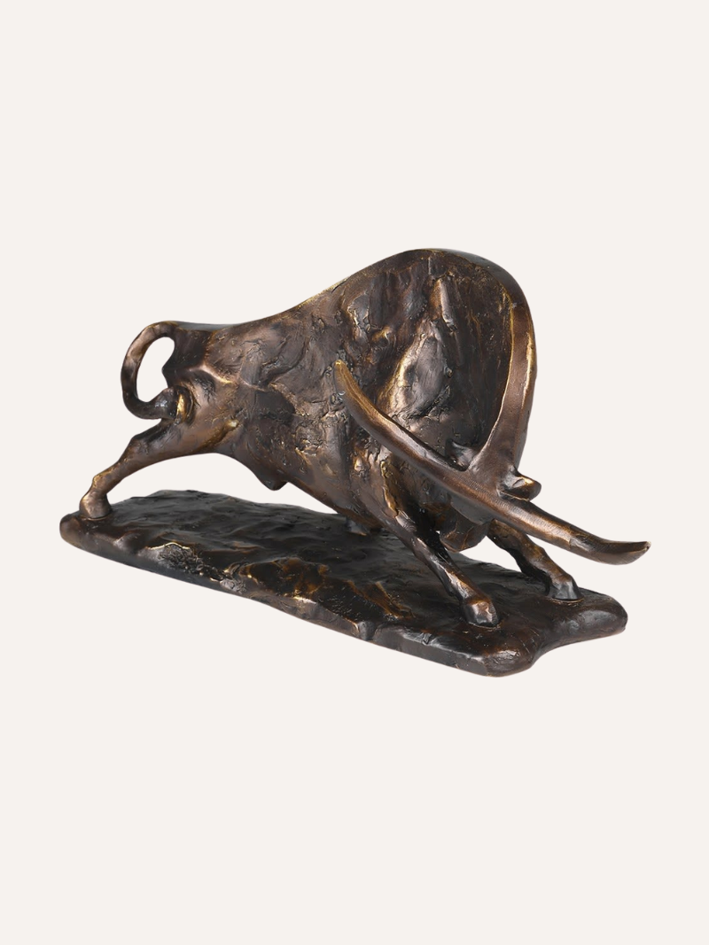 Bronze sculpture of a charging bull on a white background