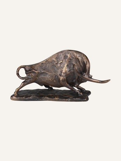 Bronze sculpture of a charging bull on a white background