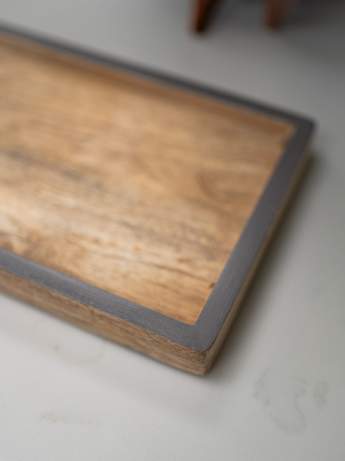 Wooden tray with a grey border on a light gray surface