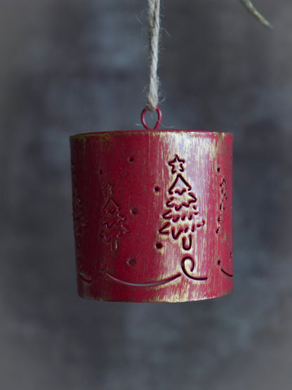 Red cylindrical hanging bell ornament with tree design on a dark background