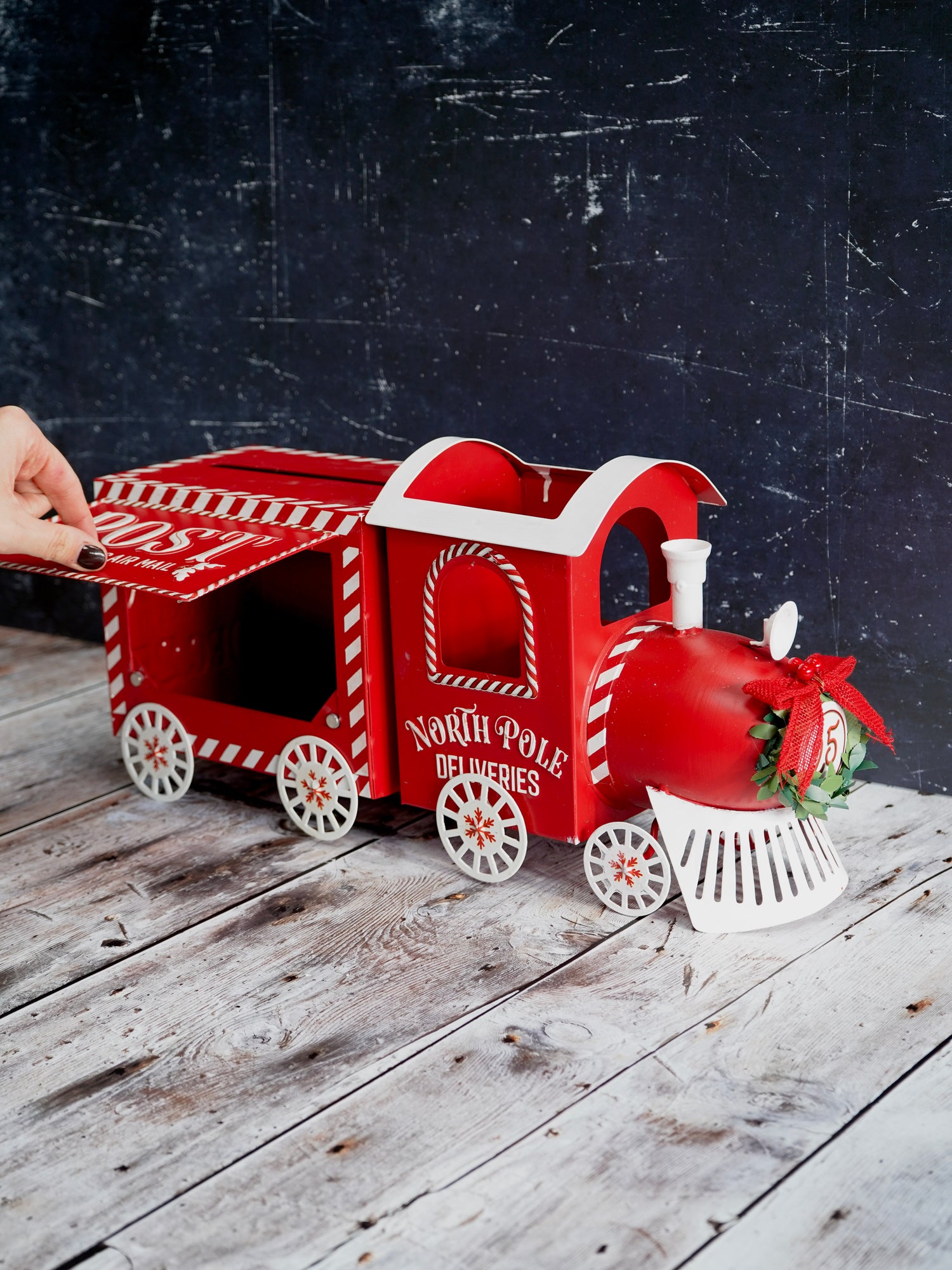 Red toy train with a decorative bow on a wooden surface against a dark background