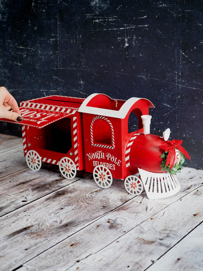 Red toy train with a decorative bow on a wooden surface against a dark background