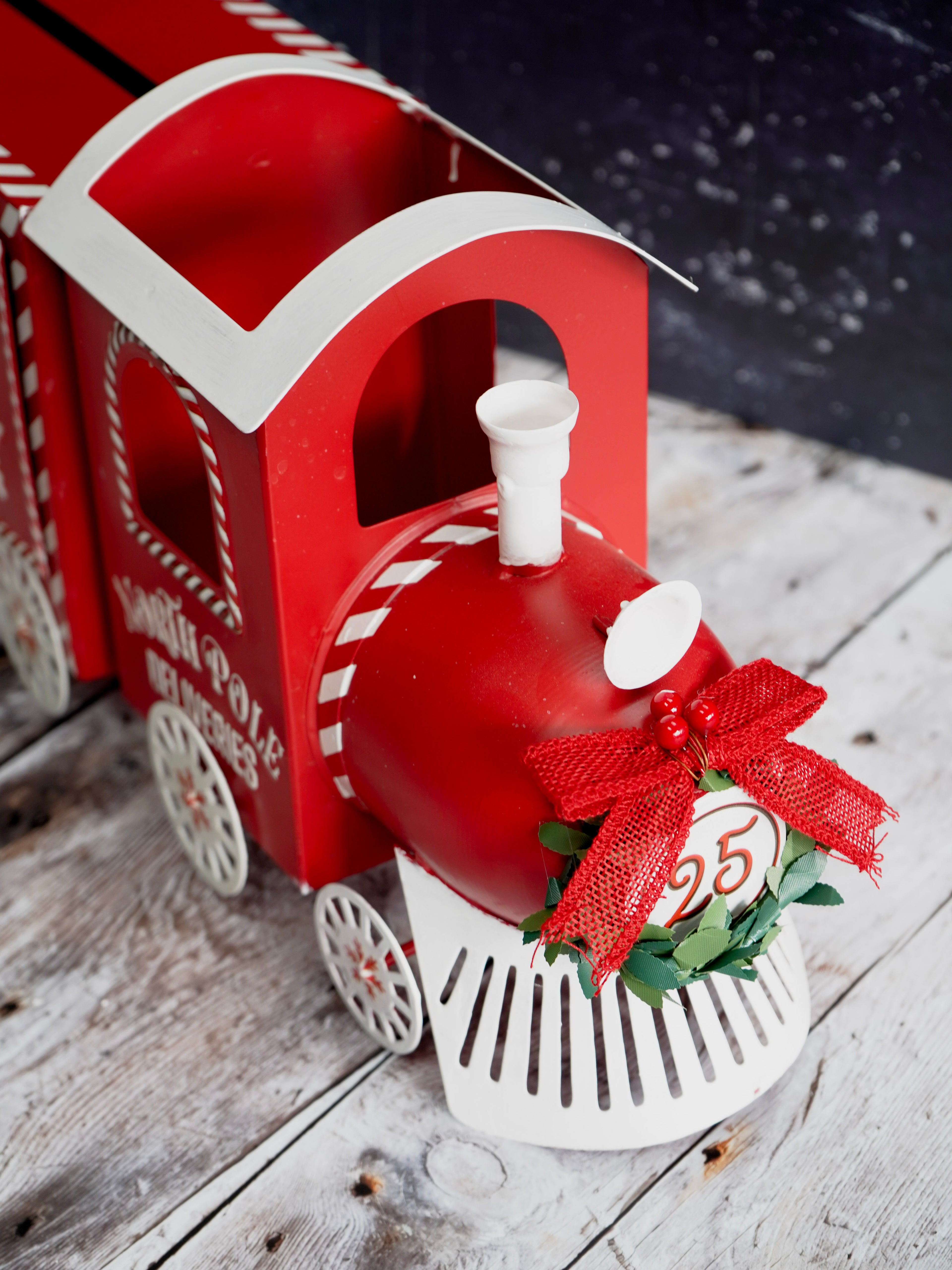 Red and white train-shaped decoration with a red bow and number 25 on a wooden surface.
