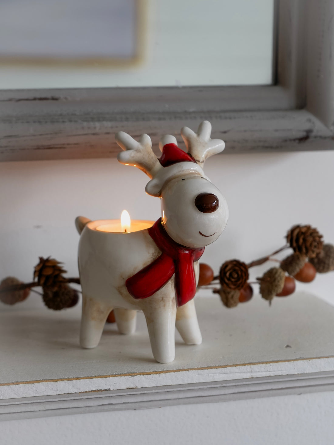 Decorative reindeer candle holder with a lit candle on a surface.