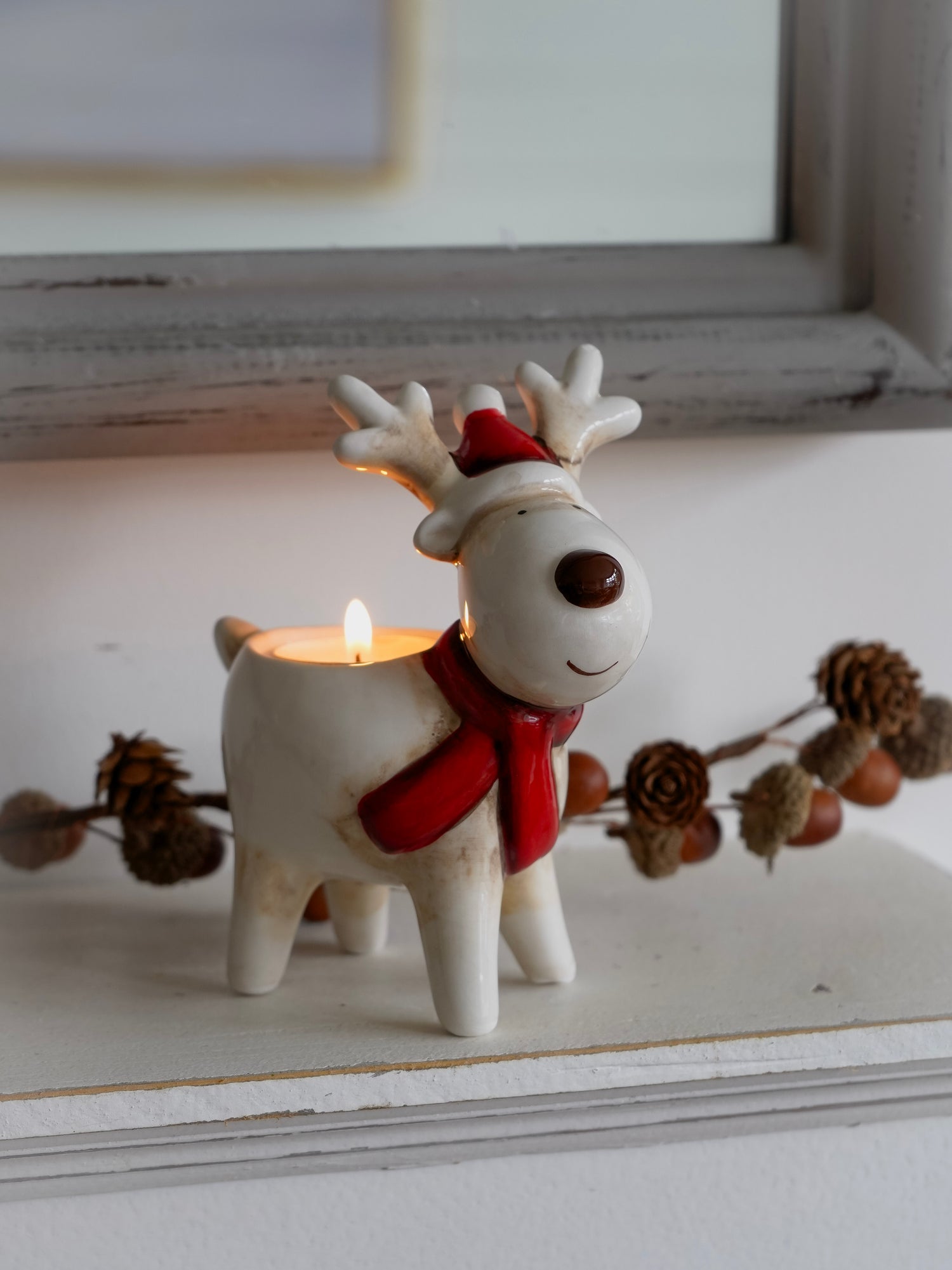 Decorative reindeer candle holder with a lit candle on a surface.